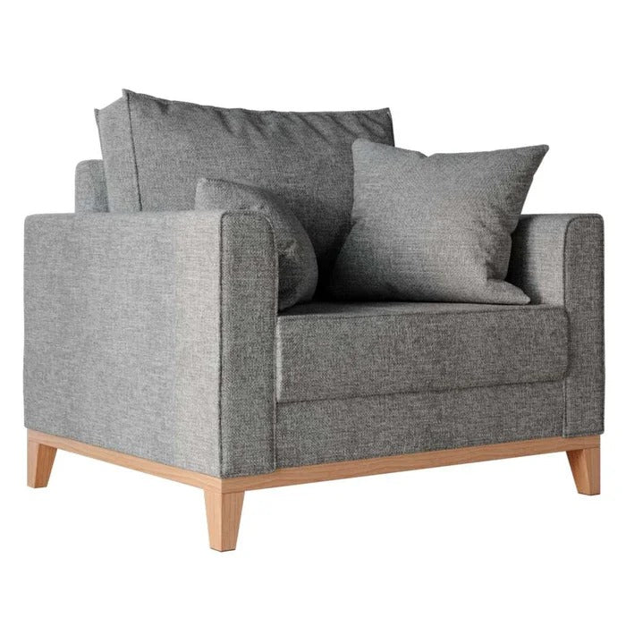 Poltrona cinza estofada vista lateral com pés de madeira clara e almofadas